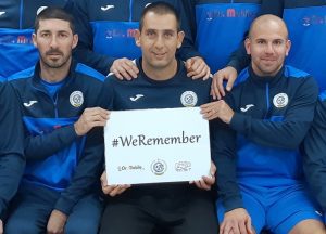 שחקני קבוצת הבוגרים "מכבי נווה שאנן אלדד" עם שלט הקמפיין "אנחנו זוכרים".
