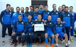 שחקני קבוצת הבוגרים "מכבי נווה שאנן אלדד" עם שלט הקמפיין "אנחנו זוכרים".