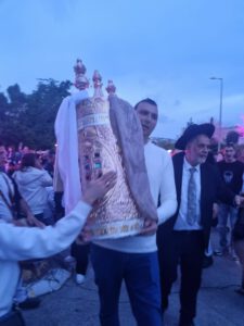 ברוב כבוד והדר: טקס הכנסת ספר תורה לבית הכנסת בבית הספרדי ספר התורה נתרם על-ידי משפחת אמויאל לעילוי נשמת אמם, דינה בת אסתר שיטרית ∙ קדמה לטקס תהלוכה שמחה בהשתתפות מאות בני אדם ∙ מנכ"לית הבית הספרדי, נטעלי בן: "זוהי זכות של ממש עבורנו להכניס ספר תורה לבית הכנסת" הכנסת ספר תורה היא תמיד טקס מרגש ומשמח שמבליט את נצחיותו של ספר הספרים ואת המקום המשמעותי שלו בחיים שלנו. כך היה גם אירוע הכנסת ספר התורה לעילוי נשמת דינה אמויאל בת אסתר שיטרית ז"ל שצוין ברוב כבוד והדר. האירוע החל בסיום כתיבת הספר בבית דינה אמויאל ז"ל, ונמשך בתהלוכה שמחה בהשתתפות למעלה מ-200 בני אדם לאורך הרחובות מימון וגדליהו. הכניסה אל בית הכנסת של הבית הספרדי, תוך שירת "שאו שערים ראשיכם והנשאו פתחי עולם ויבוא מלך הכבוד" וריקודים, גרמה להתרגשות רבה אצל הדיירים. עו"ד יוסף גילאור, יו"ר ועד העדה היהודית ספרדית חיפה, התרגש אף הוא לנוכח מה שהגדיר "כוחה של המסורת היהודית ספרדית אשר עוברת מדור לדור, ומעניקה לנו משמעות בימים המורכבים שבהם אנו נמצאים". בטקס נכחו דיירי הבית, ובפרט המתפללים הקבועים בבית הכנסת, בני משפחתה של דינה אמויאל, אנשי ועד העדה ואורחים נוספים. לאחר ההילולה בבית הכנסת התכנסה המשפחה לארוחת ערב מושקעת. פייטן מוכשר ליווה את הארוחה בשירים, והשלים ערב ייחודי בבית הספרדי. מנכ"לית הבית, נטעלי בן, הודתה למשפחה ואמרה: "זוהי זכות של ממש עבורנו להכניס ספר תורה לבית הכנסת שלנו. האירוע המרגש הוכיח שוב את כוחו של החיבור לקהילה".